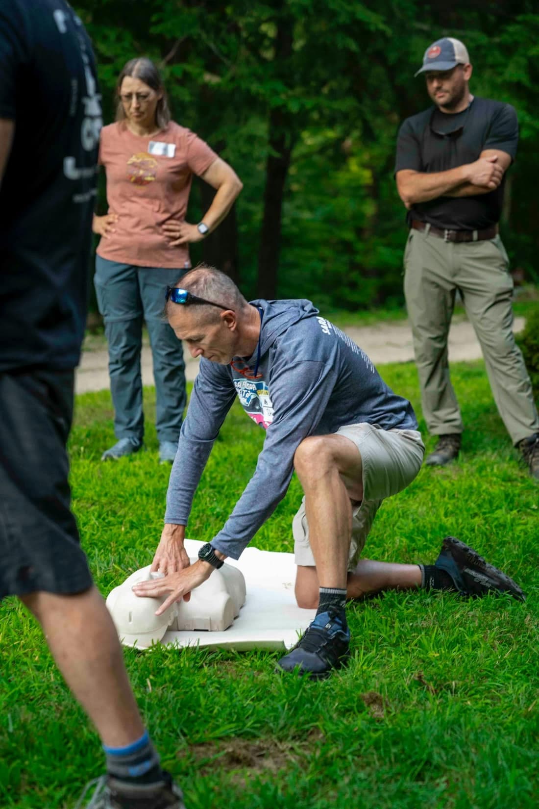 An instructor demonstrating chest compressions on a manikin while a small group watches.